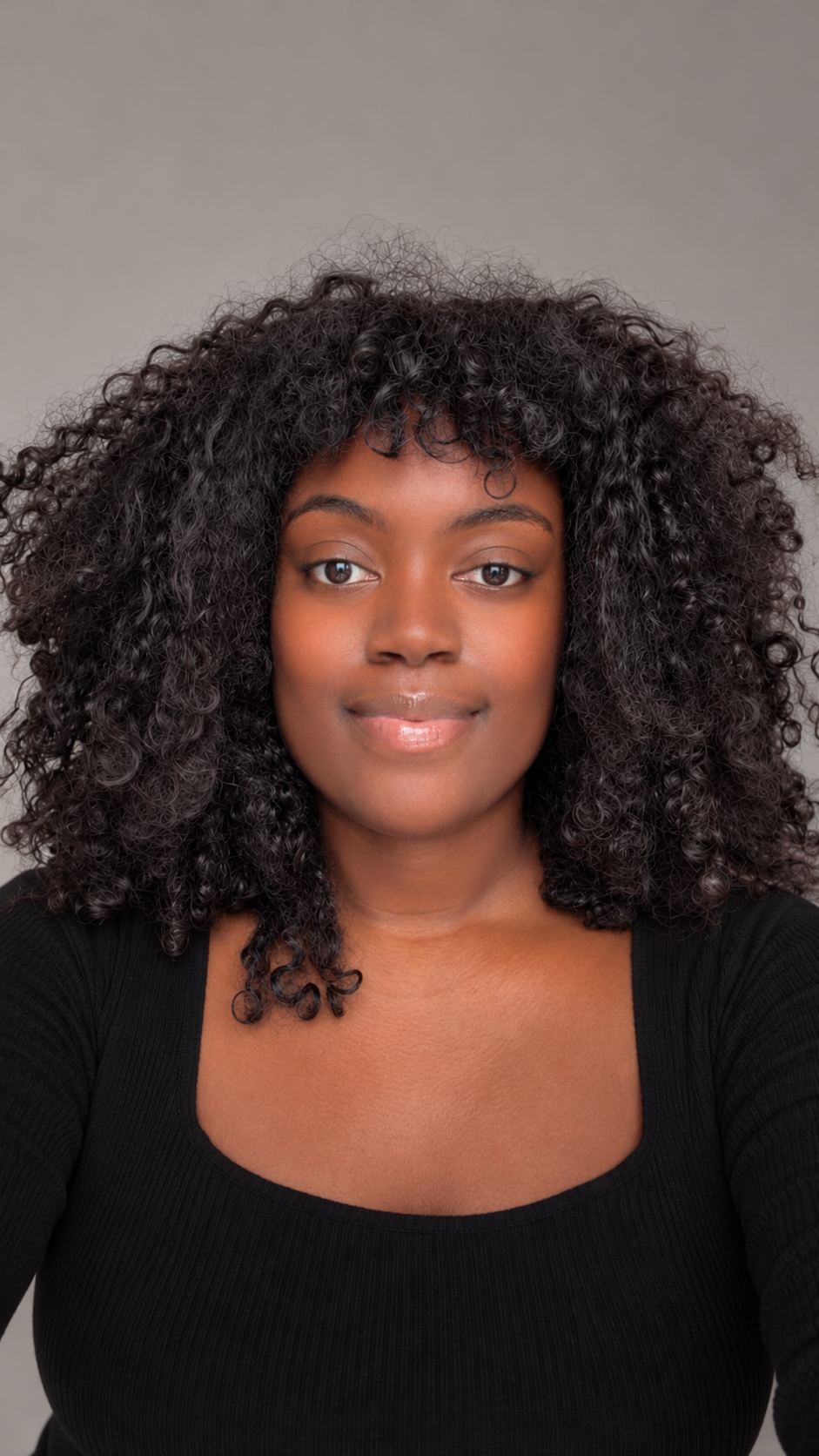 Portrait of Jullian with curly hair, wearing a black top